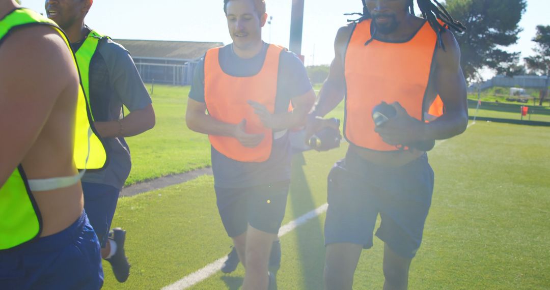 Football Players Training on Field Wearing Bright Vests - Free Images, Stock Photos and Pictures on Pikwizard.com