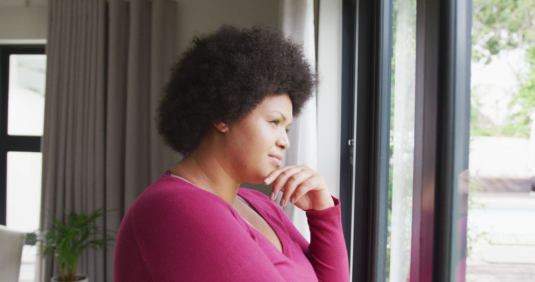 Thoughtful Woman with Afro Hair Standing by Window Contemplating - Free Images, Stock Photos and Pictures on Pikwizard.com