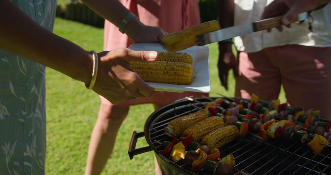 Diverse Friends Enjoying Grilled Corn and Skewers Outdoors