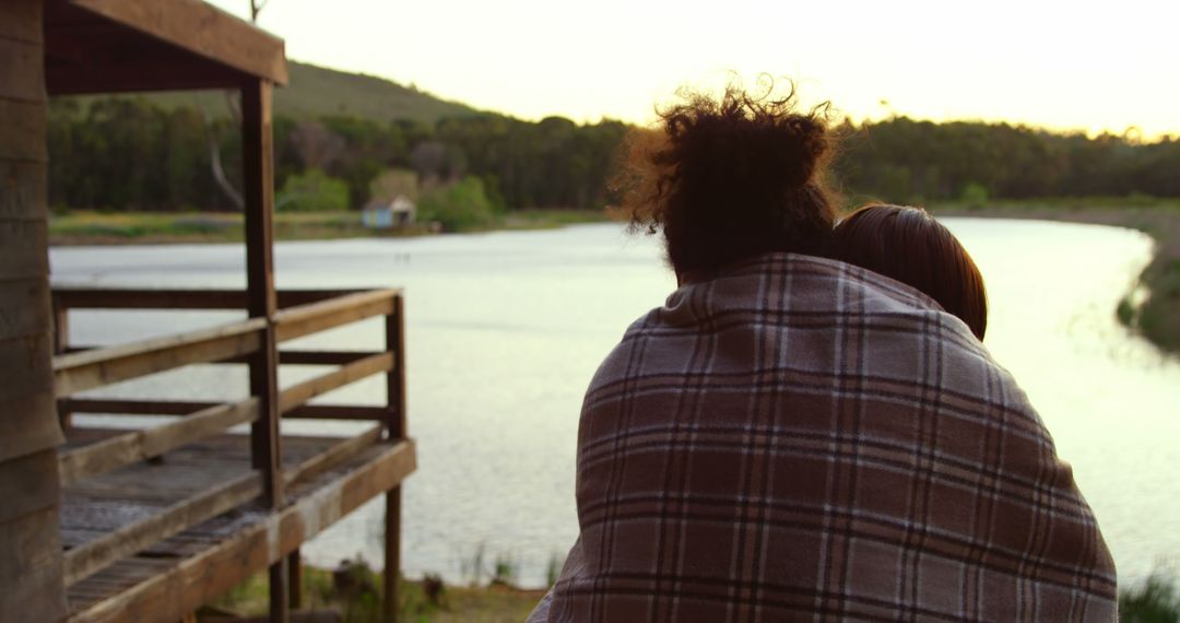 Couple Snuggling Under Blanket Near Riverside During Sunset - Free Images, Stock Photos and Pictures on Pikwizard.com