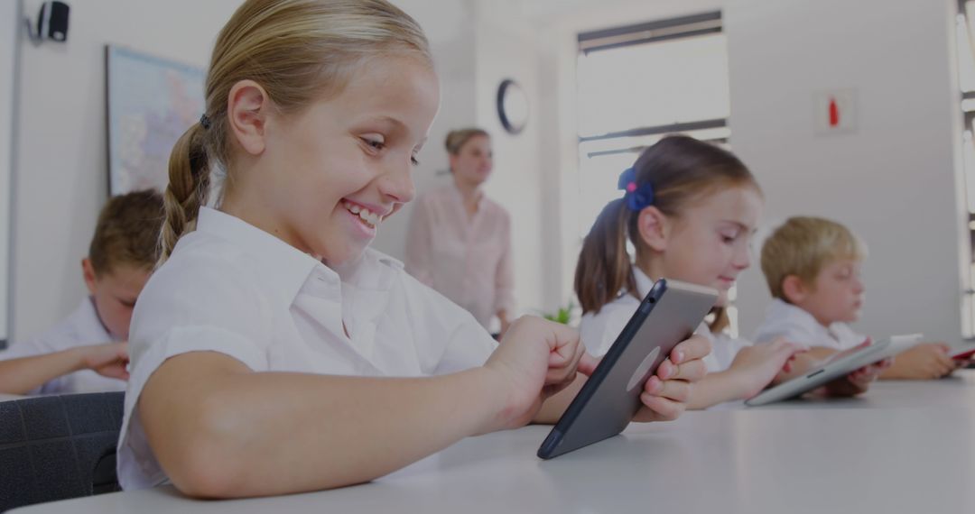 Child Using Tablet in Classroom with Teacher and Other Students