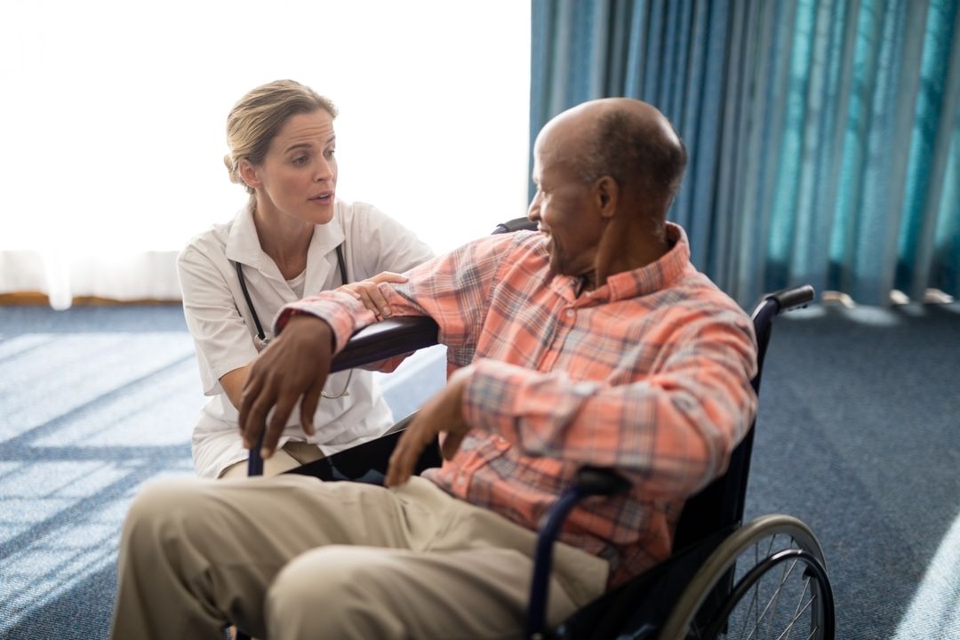 Female doctor kneeling while talking to disabled senior man on wheelchair - Free Images, Stock Photos and Pictures on Pikwizard.com