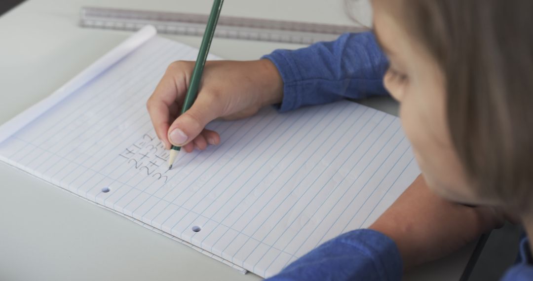 Focused Boy Practicing Division Problems in School Notebook