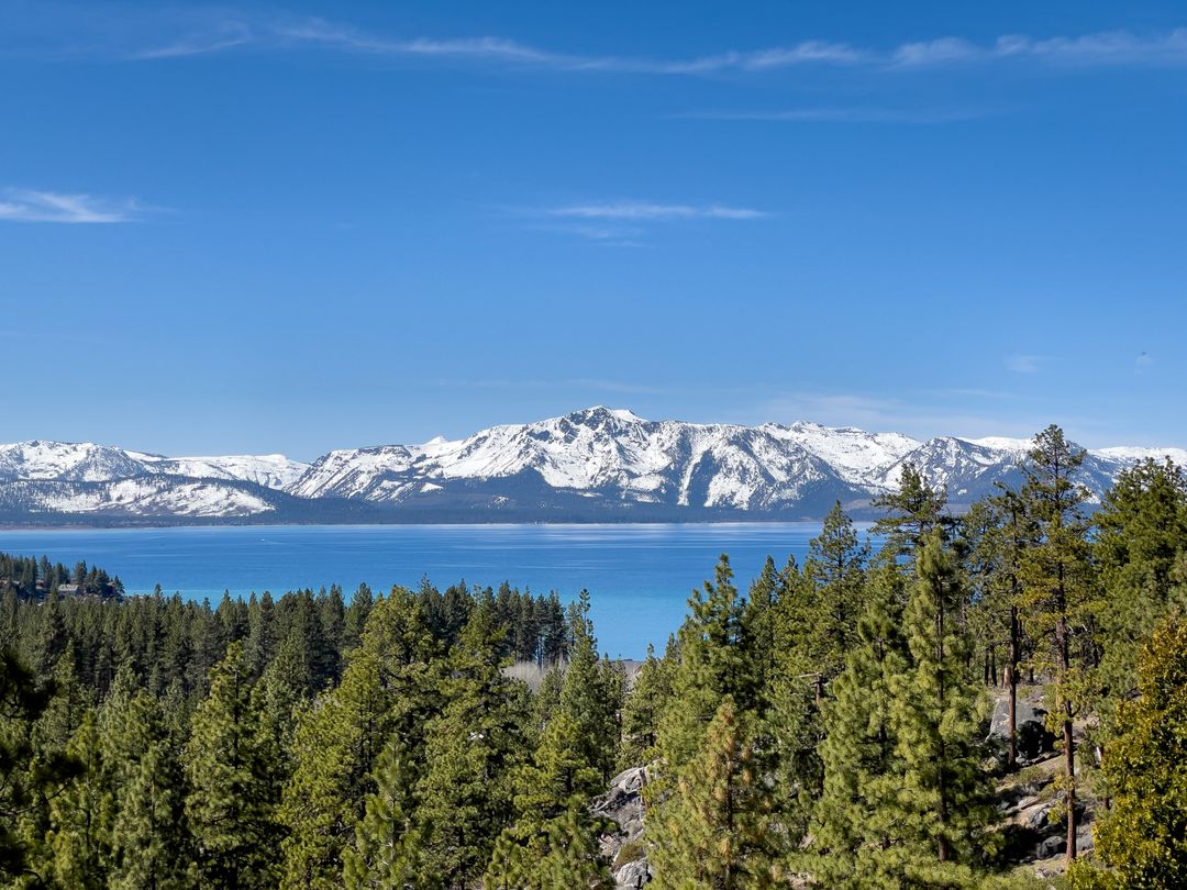 Snow-Capped Mountains Reflected in Clear Lake with Lush Forest in Foreground