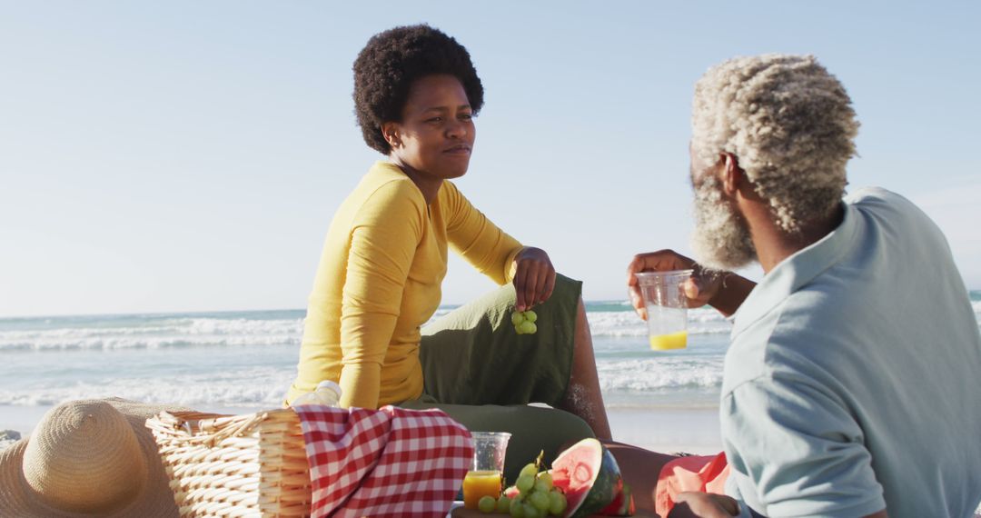 Couple Enjoying Beach Picnic with Refreshments and Fresh Fruit - Free Images, Stock Photos and Pictures on Pikwizard.com