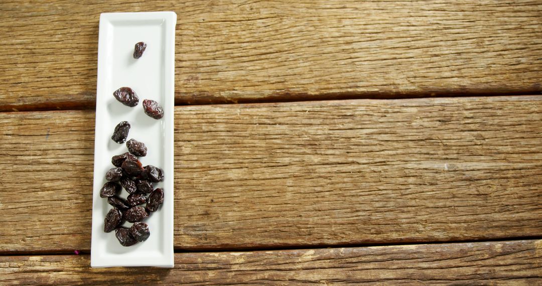 Healthy Black Raisins in White Ceramic Dish on Rustic Wooden Surface - Free Images, Stock Photos and Pictures on Pikwizard.com