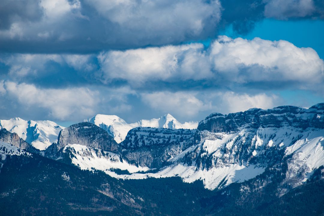 Snow-covered Mountain Range Framed by Dramatic Clouds and Crisp Blue Sky