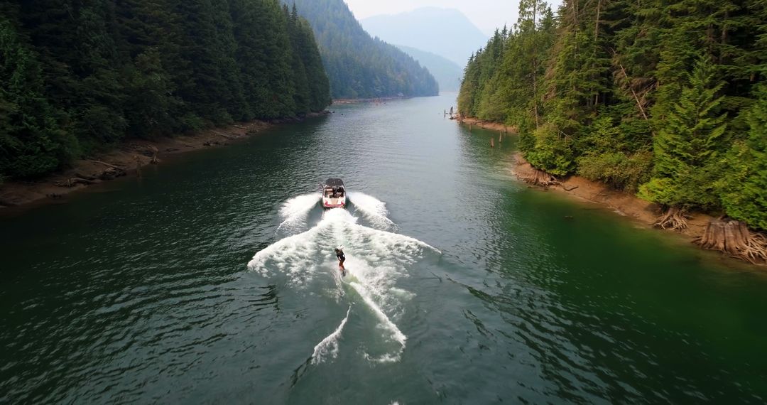 Aerial View of Person Wakeboarding on Lake Surrounded by Dense Forest - Free Images, Stock Photos and Pictures on Pikwizard.com