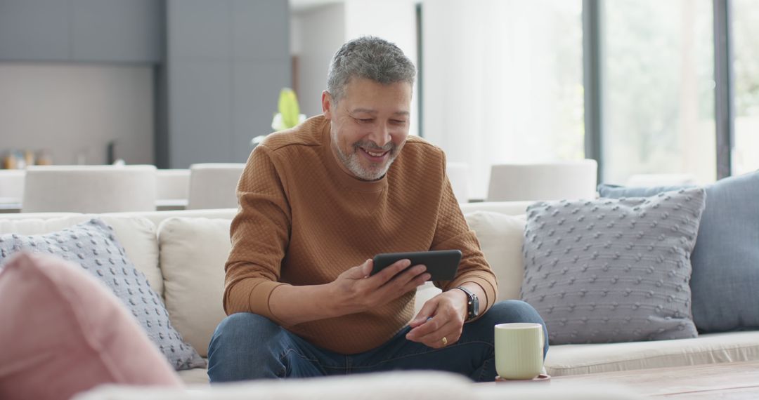 Smiling Middle-aged Man Using Tablet in Modern Living Room - Free Images, Stock Photos and Pictures on Pikwizard.com