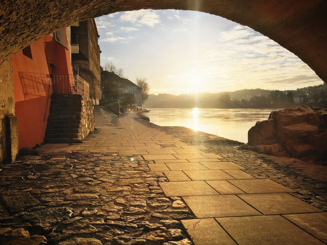 Sunlit Riverbank under Stone Archway at Dawn