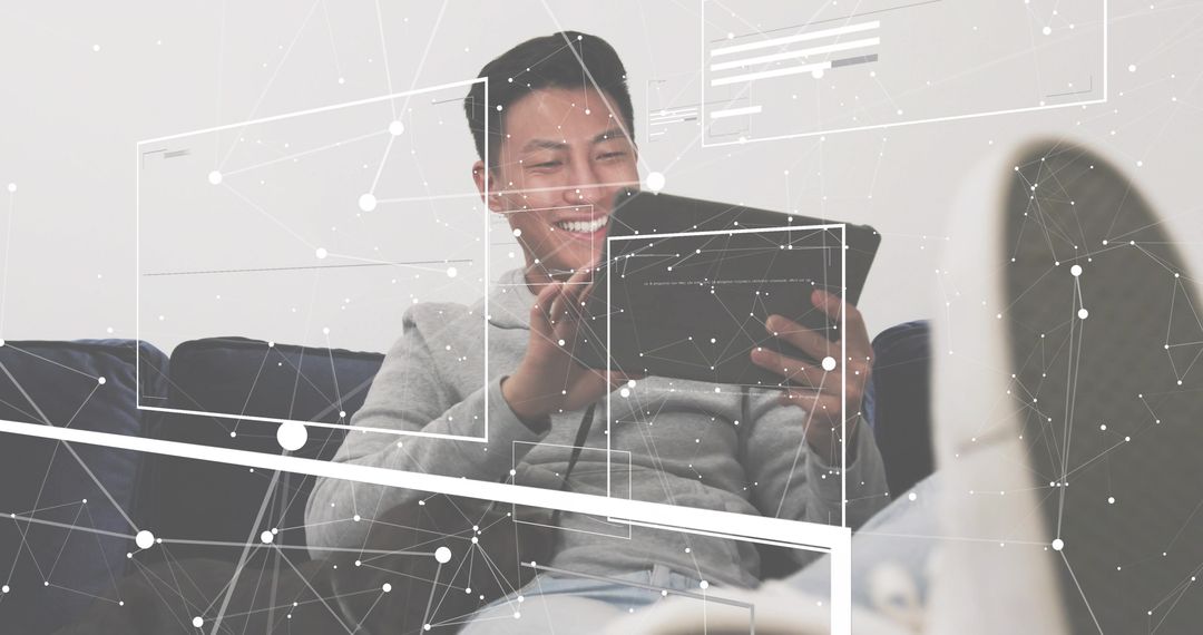 Smiling young man using tablet on couch with digital network overlay for remote connectivity