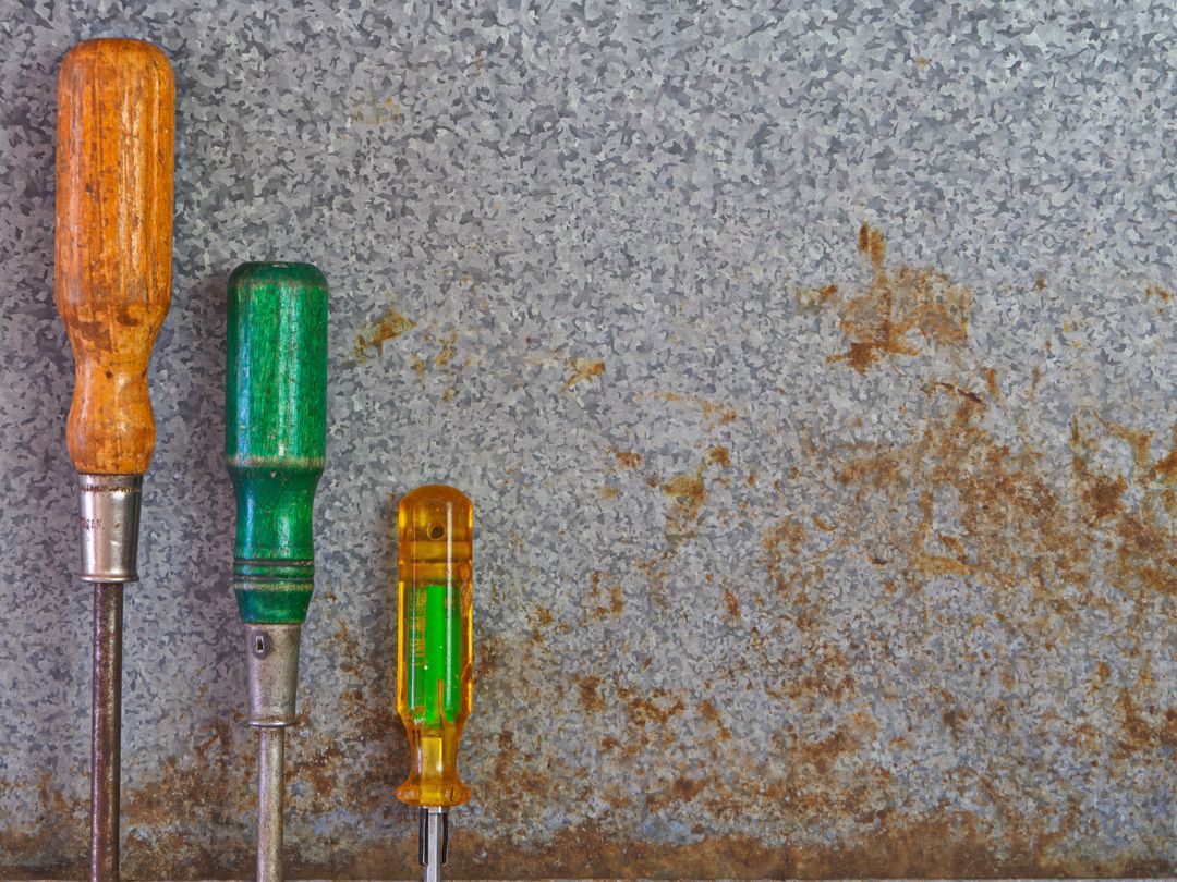 Three Rusting Screwdrivers on Weathered Surface