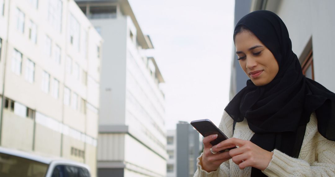 Muslim Woman Using Smartphone Outdoors in Urban Environment - Free Images, Stock Photos and Pictures on Pikwizard.com