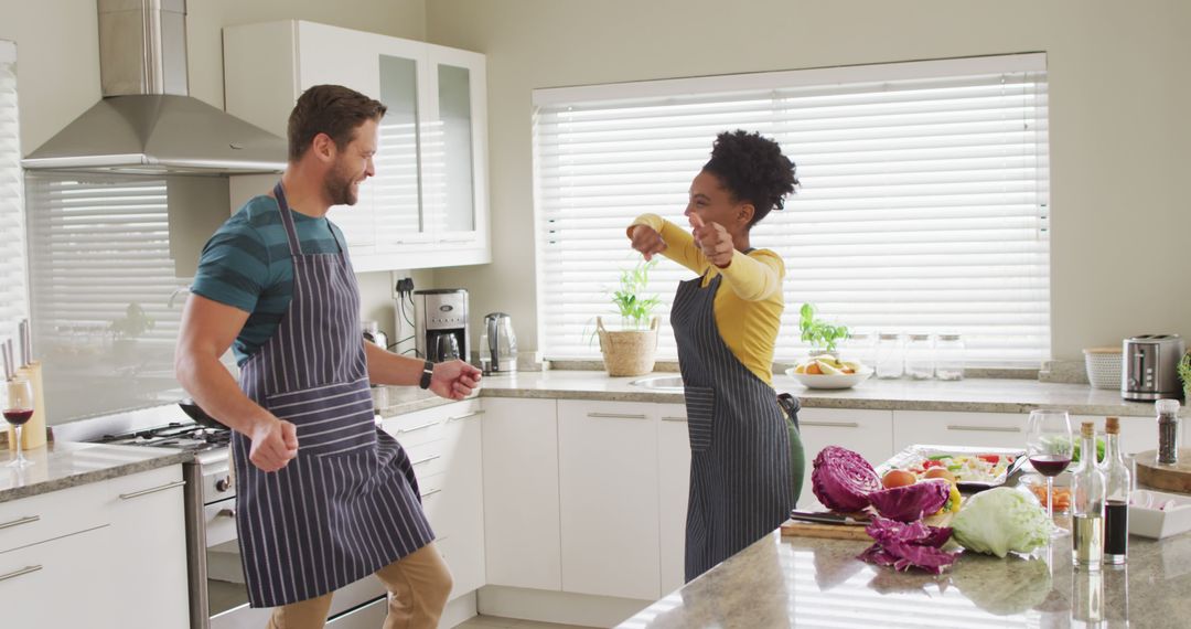 Image of happy diverse couple dancing in kitchen in aprons - Free Images, Stock Photos and Pictures on Pikwizard.com