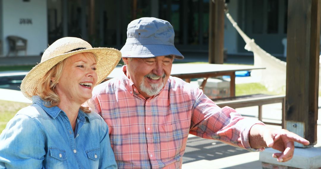 A joyful senior couple enjoys a playful conversation outdoors in hats. - Free Images, Stock Photos and Pictures on Pikwizard.com