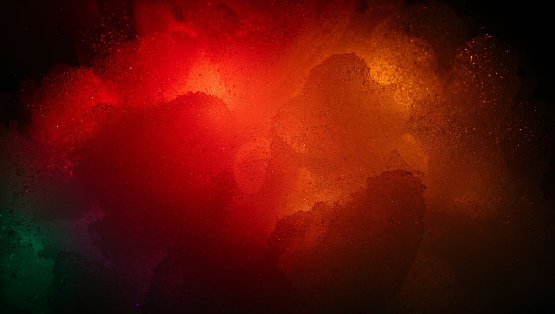 Swirling red and orange pigment cloud glowing with granular droplets and backlit mist