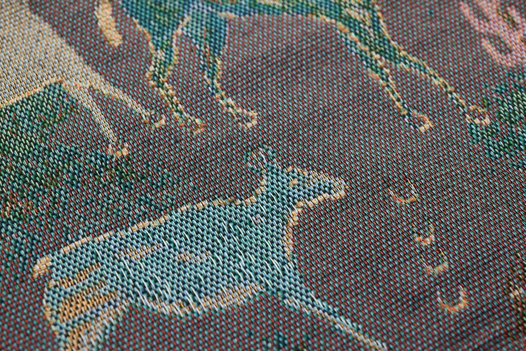 Close-up of woven jacquard fabric with deer motif showing colorful threads and texture