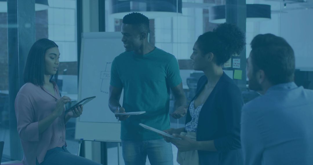 Diverse team collaborating around flipchart with tablets during modern office brainstorming