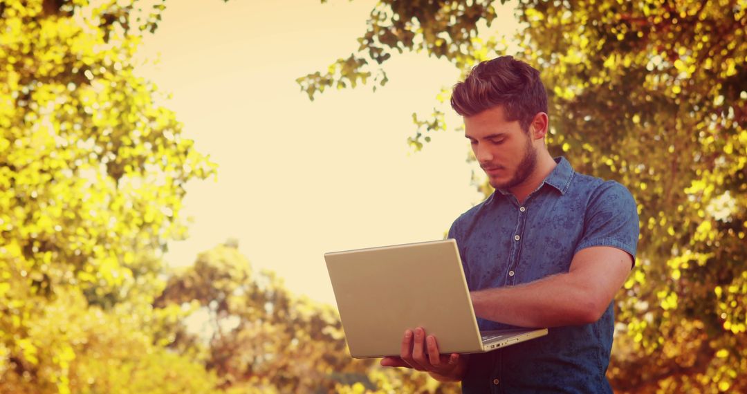 Young Man Using Laptop in Outdoor Park Setting - Free Images, Stock Photos and Pictures on Pikwizard.com