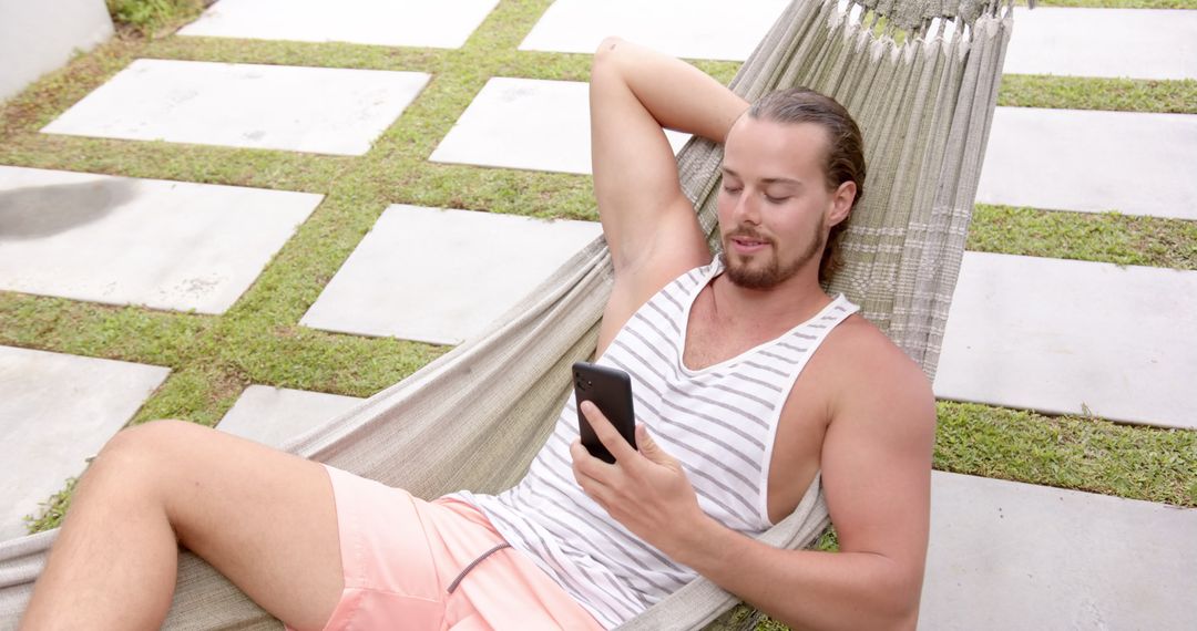 Young Man Enjoying a Peaceful Hammock Break with Smartphone Outdoors