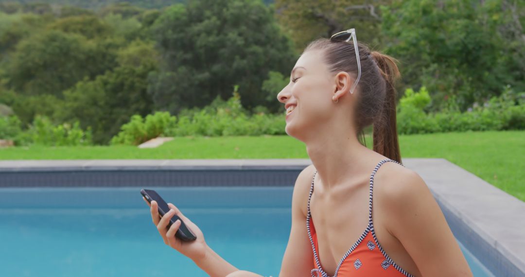 Young Woman Relaxing by Pool with Smartphone and Smiling - Free Images, Stock Photos and Pictures on Pikwizard.com