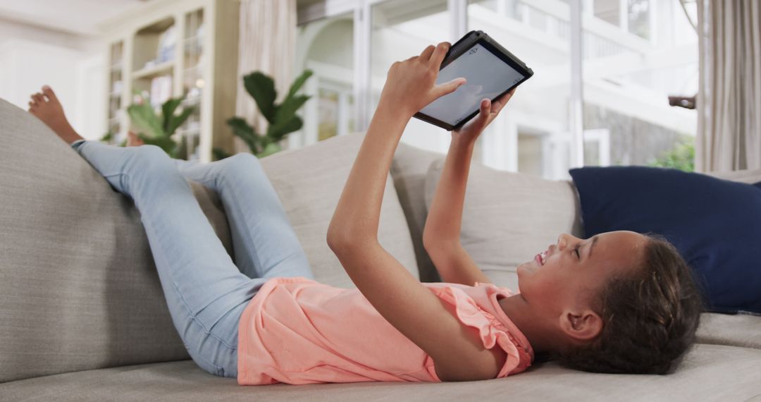 Young girl relaxing on sofa using tablet at home - Free Images, Stock Photos and Pictures on Pikwizard.com