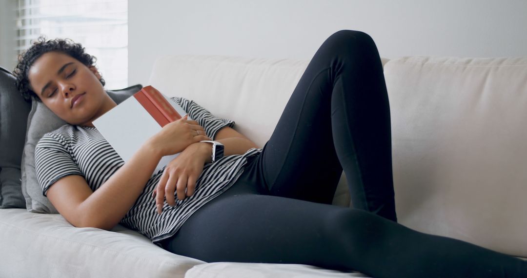 Young Woman Napping on Sofa Holding Book in Living Room - Free Images, Stock Photos and Pictures on Pikwizard.com