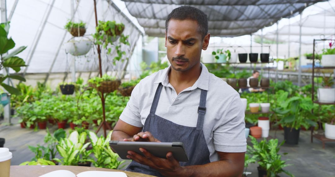Botanist Using Tablet in Greenhouse Surrounded by Lush Plants