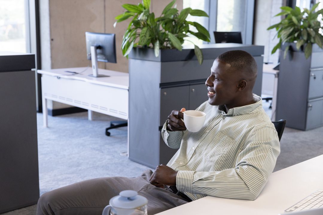 Smiling Office Worker Enjoying Coffee Break in Modern Open Office