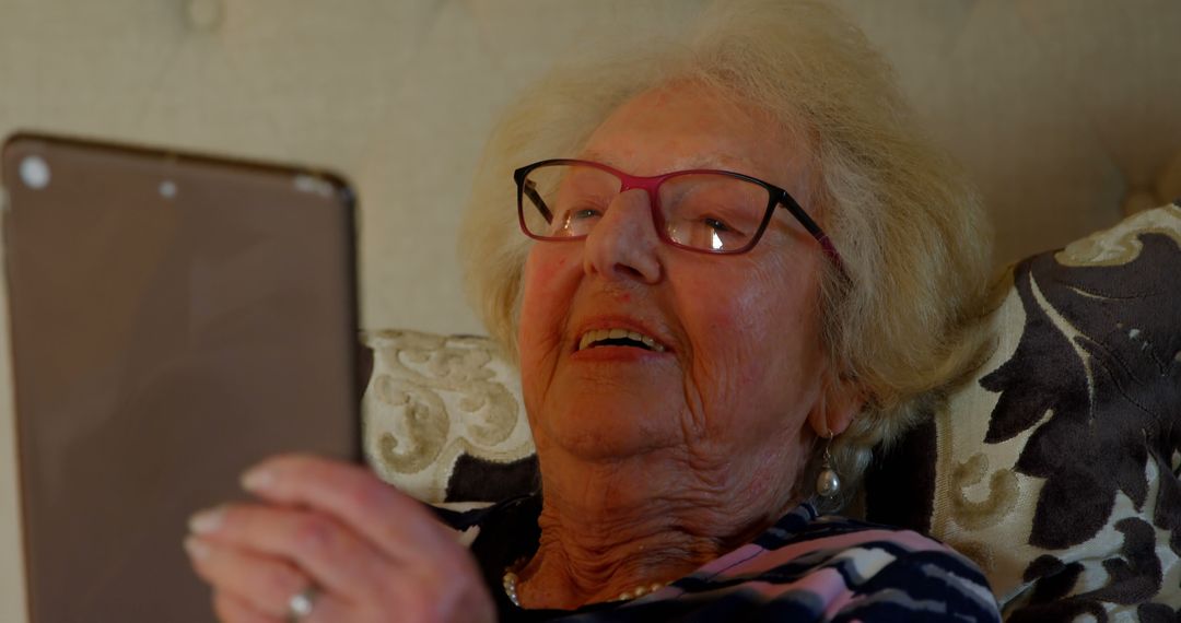 Elderly Woman Using Tablet While Lying Down, Leisure Time at Home - Free Images, Stock Photos and Pictures on Pikwizard.com