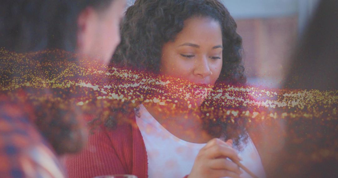 Woman enjoying casual dinner in red cardigan with golden bokeh, intimate meal