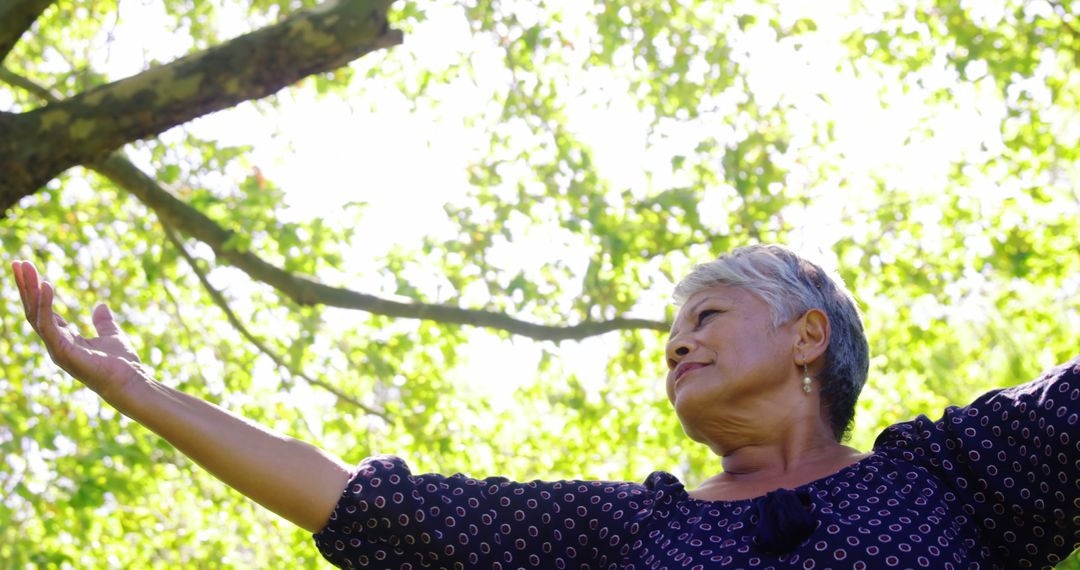 Elderly Woman Enjoying Nature with Arms Outstretched Under Tree - Free Images, Stock Photos and Pictures on Pikwizard.com