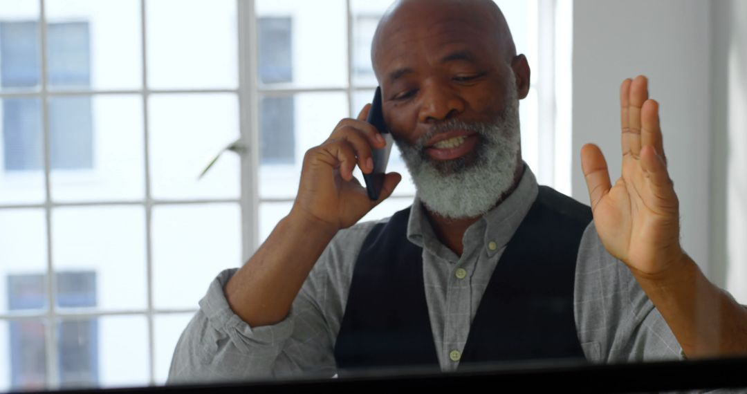 Mature African American Man Having a Phone Conversation in Modern Office - Free Images, Stock Photos and Pictures on Pikwizard.com