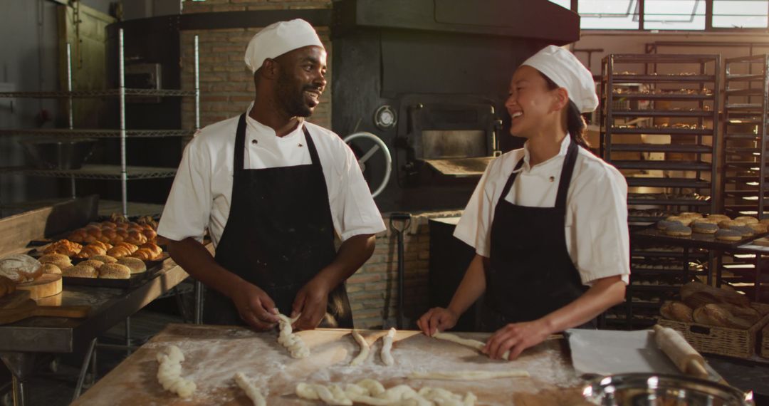 Diverse bakers in commercial kitchen working together smiling - Free Images, Stock Photos and Pictures on Pikwizard.com