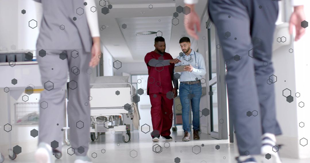 Healthcare Team Walking and Examining Tablet in Bright Hospital Corridor with Gurney