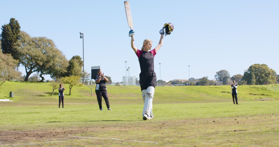 Female Cricketer Celebrating on Field with Team Applause