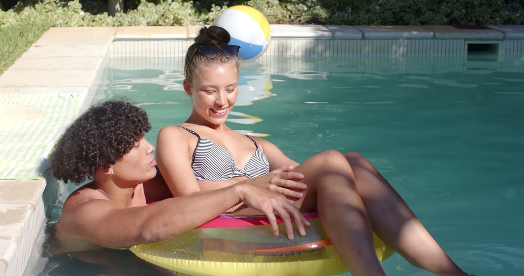 Joyful Couple Relaxing in Pool with Inflatable and Beach Ball
