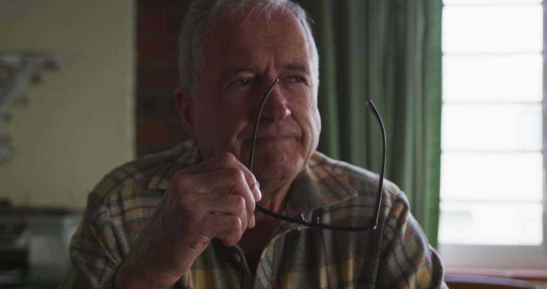 Elderly Man Reflecting Holding Glasses by Window - Free Images, Stock Photos and Pictures on Pikwizard.com