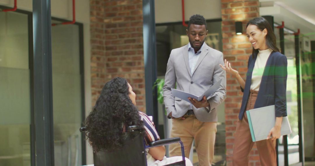 Co-workers Collaborating with Team Member in Wheelchair at Modern Office