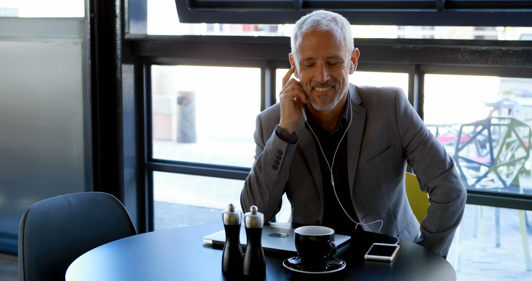 Mature Businessman Listening to Music in Coffee Shop - Free Images, Stock Photos and Pictures on Pikwizard.com