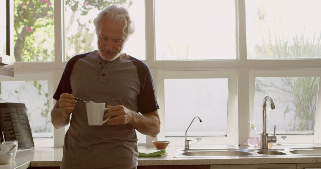 Senior man enjoying morning coffee in bright kitchen - Free Images, Stock Photos and Pictures on Pikwizard.com