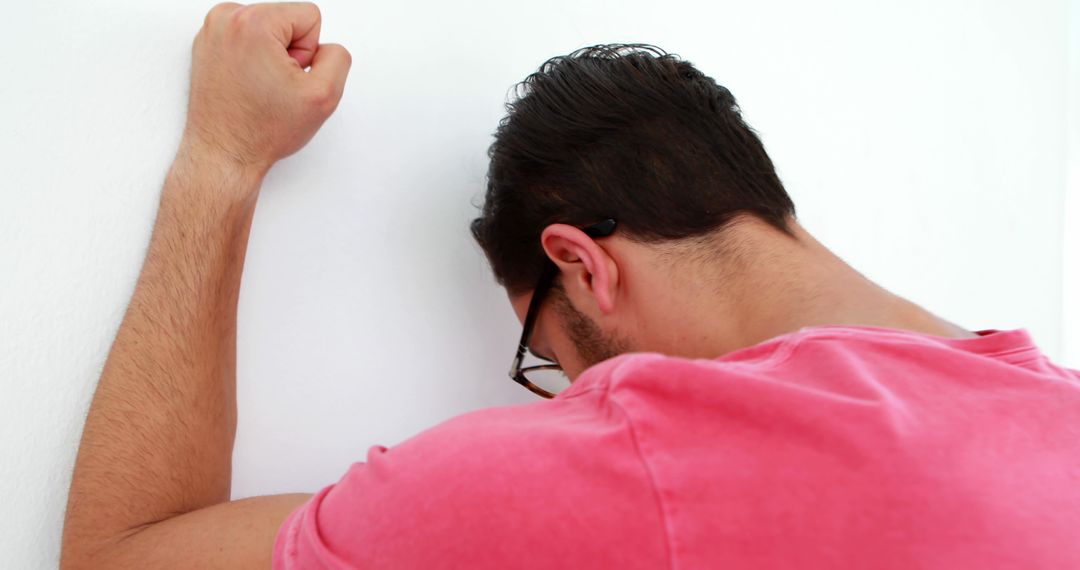 A young man exhibits signs of distress, pressing his forehead against a wall in frustration. - Free Images, Stock Photos and Pictures on Pikwizard.com