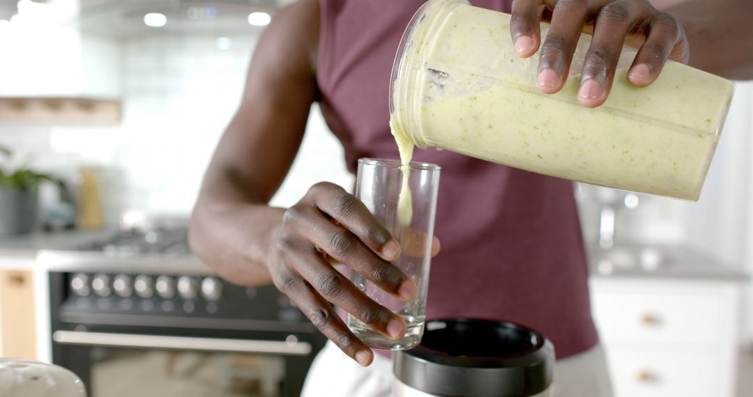 Healthy Lifestyle Man Pouring Green Smoothie into Glass in Kitchen - Free Images, Stock Photos and Pictures on Pikwizard.com