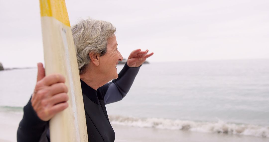 Senior Woman Holding Surfboard at Beach Looking to Horizon - Free Images, Stock Photos and Pictures on Pikwizard.com