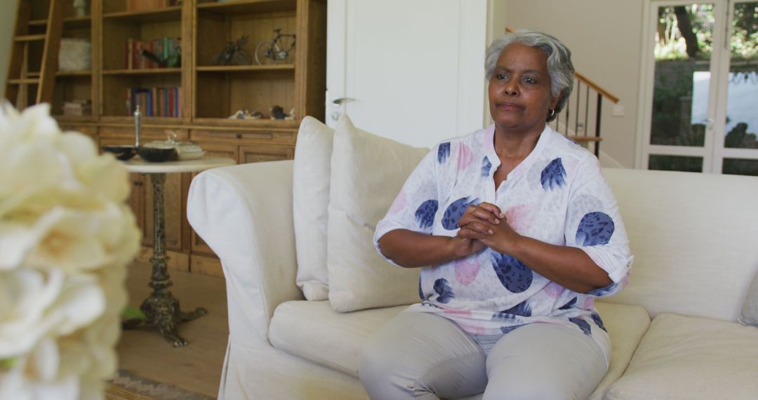 Worried african american senior woman sitting on the couch at home - Free Images, Stock Photos and Pictures on Pikwizard.com