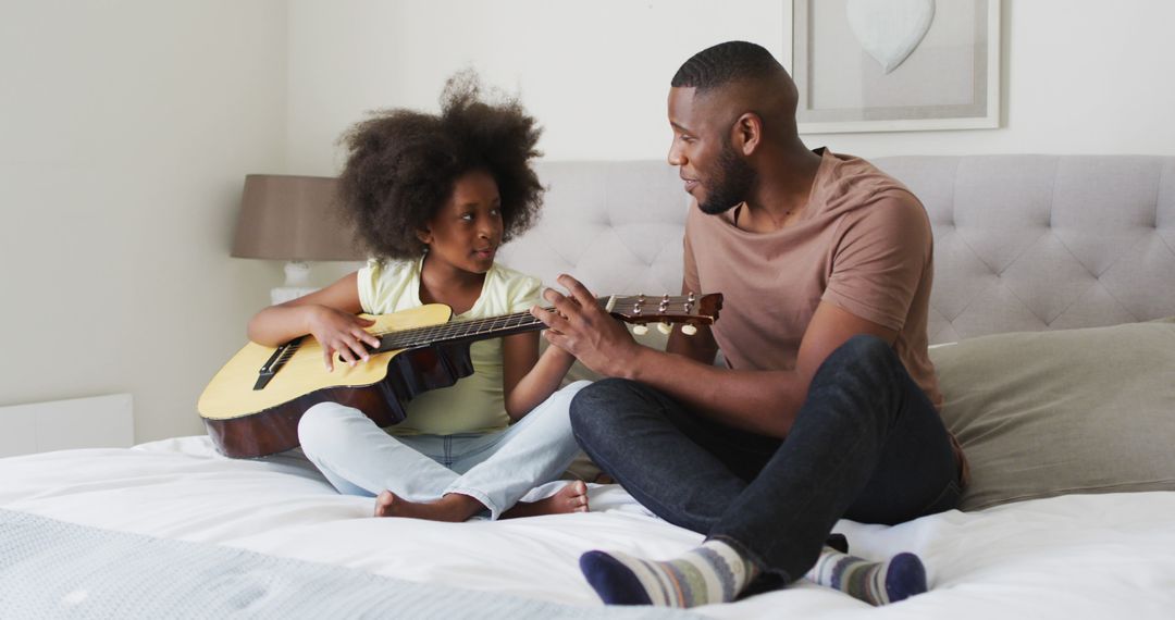 Father Teaching Daughter How to Play Guitar on Bed - Free Images, Stock Photos and Pictures on Pikwizard.com