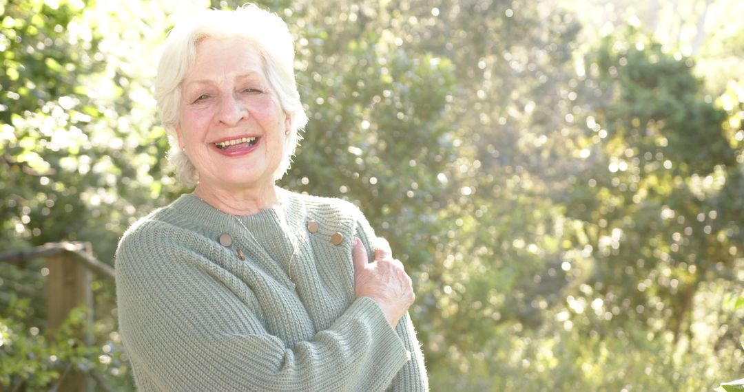 Laughing Senior Woman in Sweater Enjoying Sunny Forest - Free Images, Stock Photos and Pictures on Pikwizard.com