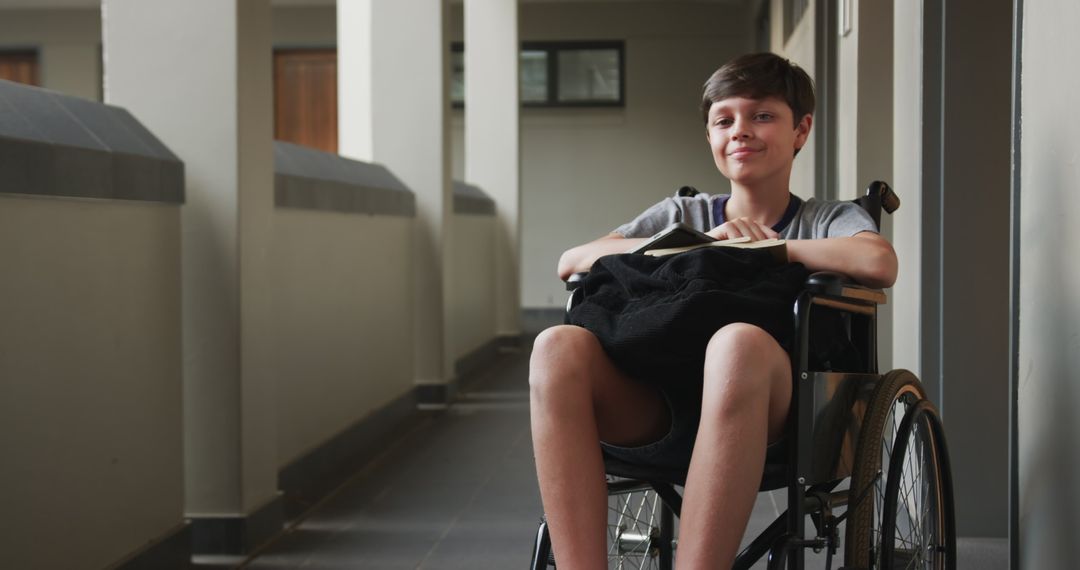 Confident Boy in Wheelchair Holds Notebook in Modern Corridor