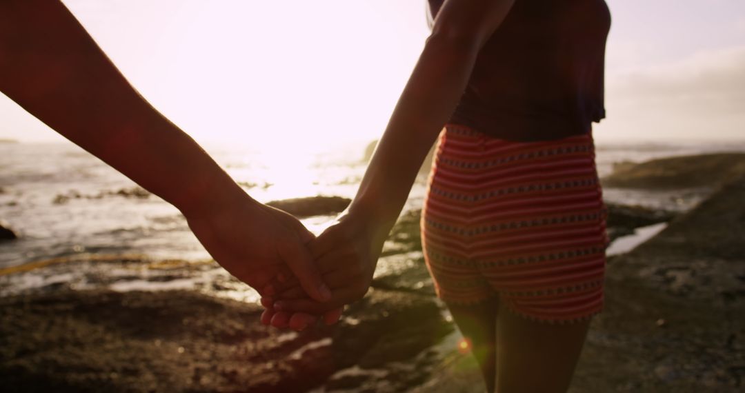 Couple Holding Hands Walking on Beach at Sunset