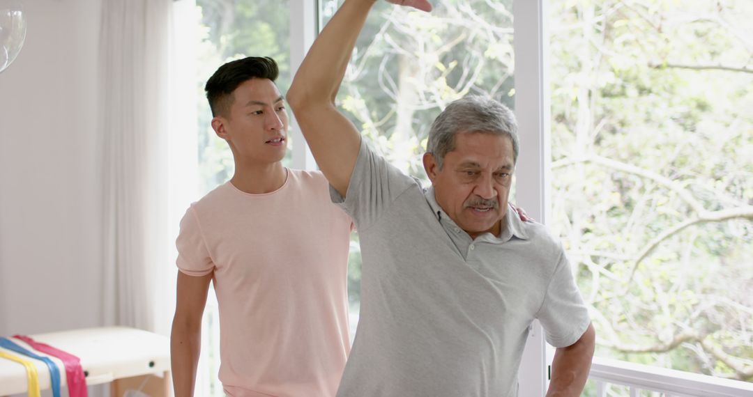 Physical Therapist Assisting Elderly Man with Arm Exercise at Home - Free Images, Stock Photos and Pictures on Pikwizard.com